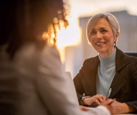 Two women facing one another, one smiling at the other